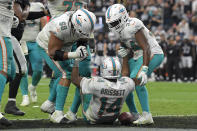 Miami Dolphins offensive guard Robert Hunt (68) and running back Malcolm Brown (34) help up quarterback Jacoby Brissett (14) after Brissett scored a touchdown against the Las Vegas Raiders during the second half of an NFL football game, Sunday, Sept. 26, 2021, in Las Vegas. (AP Photo/David Becker)