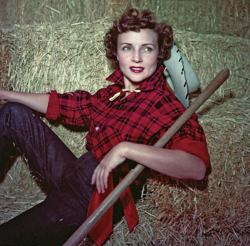 <p>White poses for a photograph in a plaid shirt and cowboy hat.</p>