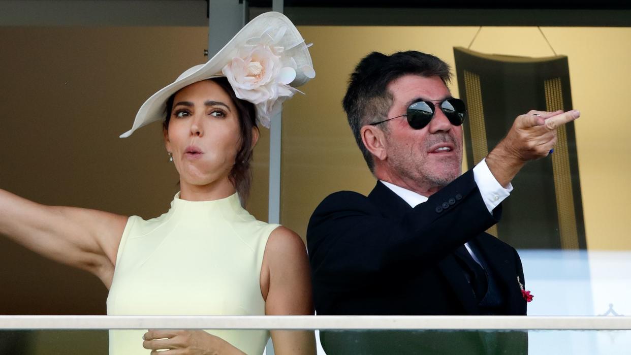 Simon Cowell and Lauren Silverman pointing in opposite directions