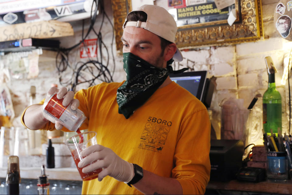 FMN General Store managing partner Derek Tigue makes a bloody mary behind the bar at the former Forgtmenot, which he, his partners and friends converted into a mini grocery store selling produce, groceries and household staples to customers during the current coronavirus outbreak, Wednesday, April 15, 2020, in New York. (AP Photo/Kathy Willens)