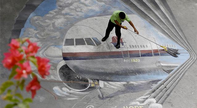 a school utility worker mops a mural depicting the missing Malaysia Airlines Flight 370 Tuesday, April 8, 2014 at the Benigno 