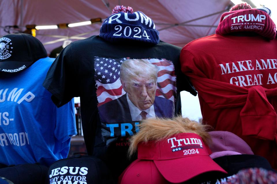 Shirts and hats are seen at a vendor stand before a former President Donald Trump commit to caucus rally, Wednesday, Dec. 13, 2023, in Coralville, Iowa. (AP Photo/Charlie Neibergall)
