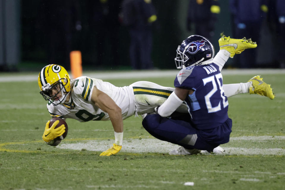 Green Bay Packers wide receiver Christian Watson (9) is stopped after making a catch by Tennessee Titans safety Joshua Kalu (28) during the second half of an NFL football game Thursday, Nov. 17, 2022, in Green Bay, Wis. (AP Photo/Mike Roemer)