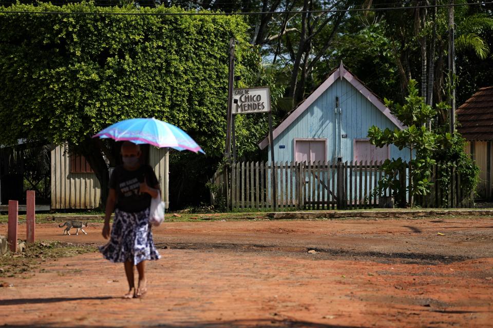 A woman walks in front of the house where environmentalist leader and rubber-tapper Chico Mendes was murdered, in Xapuri, Acre state, Brazil, Tuesday, Dec. 6, 2022. The reserve is forest protected in his name. (AP Photo/Eraldo Peres)