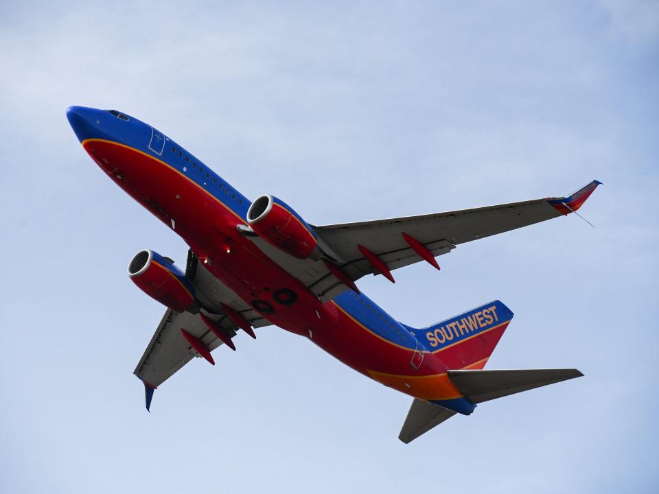 A Southwest Airlines airplane takes off in front of a blue sky