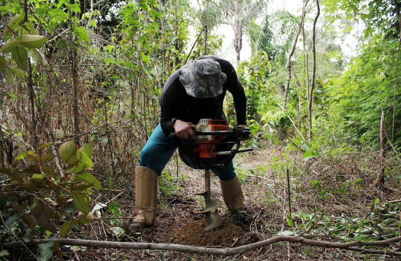 Day laborer Ivan Batista Queiroz helps take soil samples while measuring carbon content on a parcel of Amazon rainforest in Itapua do Oeste