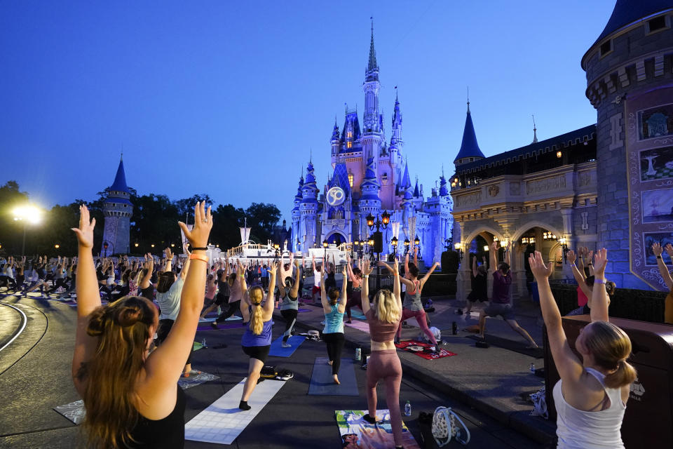 Nearly 2,000 Cast Members practice sunrise yoga celebrating International Yoga Day in front of Cinderella Castle at the Magic Kingdom Park at Walt Disney World Tuesday, June 21, 2022, in Lake Buena Vista, Fla. (AP Photo/John Raoux)