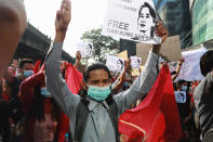 A protester flashes the three-fingered salute while holding a sign with an image of deposed Myanmar leader Aung San Suu Kyi in Yangon, Myanmar on Sunday, Feb. 7, 2021. Thousands of people rallied against the military takeover in Myanmar's biggest city on Sunday and demanded the release of Aung San Suu Kyi, whose elected government was toppled by the army that also imposed an internet blackout. (AP Photo)