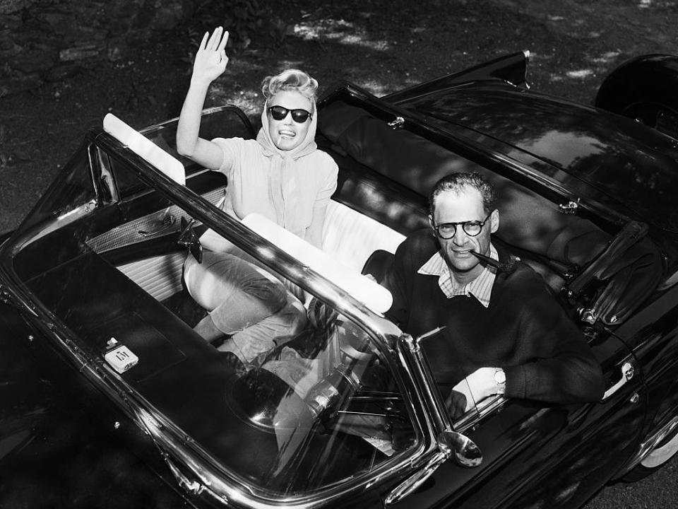 Marilyn Monroe waves from Arthur Miller's convertible as the newlyweds leave their Roxbury, Connecticut home for a picnic on the day after their wedding.