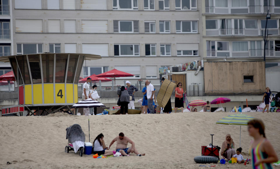 People sit on the beach at the Belgian seaside resort of Blankenberge, Belgium, Tuesday, Aug. 11, 2020. A skirmish took place on the beach on Saturday, Aug. 8, 2020 which resulted in two coastal communities banning day trippers from the city. (AP Photo/Virginia Mayo)