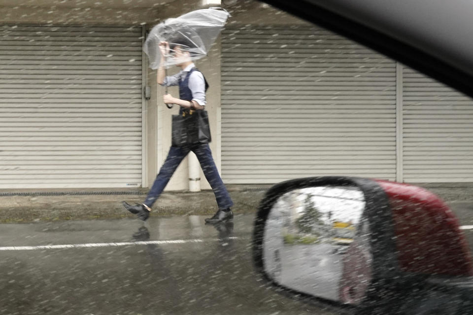 A person holds an umbrella against strong wind and rain as he walks on a street Friday, June 2, 2023, in Tokyo, as a tropical storm was approaching. (AP Photo/Eugene Hoshiko)