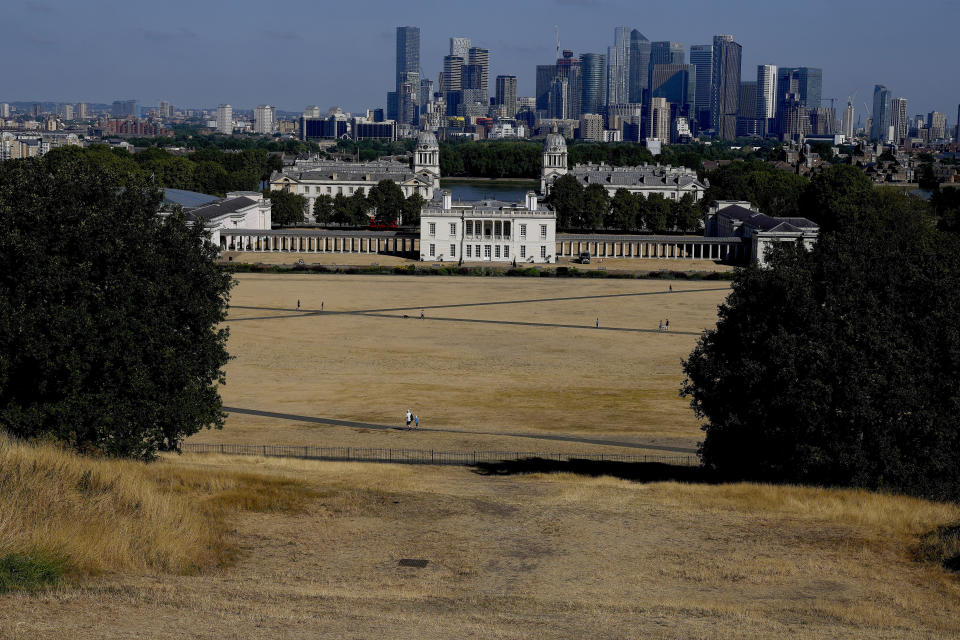 FILE - Dry and sun burnt grass spreads in Greenwich Park with the backdrop of Queens House and the high risers of Canary Wharf in London, Tuesday, Aug. 9, 2022. Britain is braced for another heatwave that will last longer than July's record-breaking hot spell, with highs of up to 35 C expected next week. (AP Photo/Frank Augstein, File)