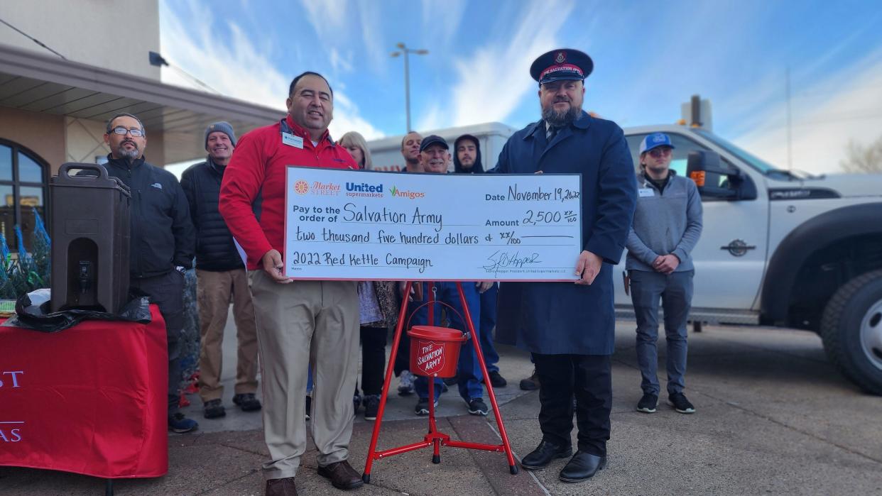 Major Tex Ellis accepts a donation check from United Supermarkets Store Director Fernando Noriega Saturday at the Salvation Army's Red Kettle kick-off event in southwest Amarillo.