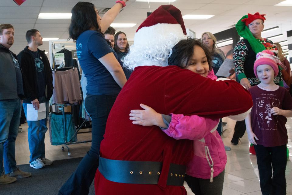 Selena Espinoza, a pre-kindergarten student at Pine Ridge, gives Santa Claus a hug before beginning her shopping spree with Advisors Excel employees Wednesday at Kohl's.