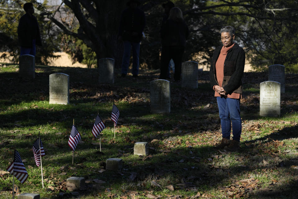 Thelma Sims Dukes observes small American flags by grave markers of Civil War soldiers of the United States 1st Mississippi Infantry (African Descent) in Vicksburg National Cemetery, Feb. 14, 2024, in Vicksburg, Miss. Thirteen flags were placed at the graves of the Black soldiers killed in an 1864 massacre at Ross Landing, Arkansas, who were buried as unknowns but have recently been identified. As a child, Dukes walked to school across the grounds of Vicksburg National Military Park. (AP Photo/Rogelio V. Solis)