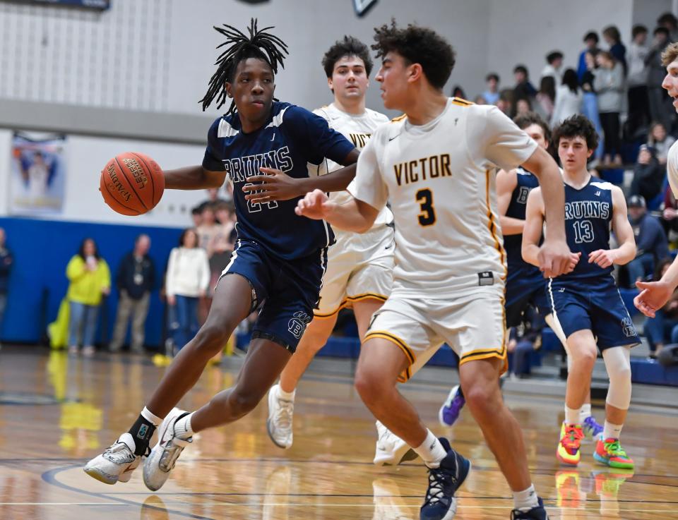 Brighton's Reggie Smith Jr., left, drives to the basket behind Victor's AJ Queri during a regular season game at Victor High School, Friday, Feb. 10, 2023. Victor beat Brighton 58-50.