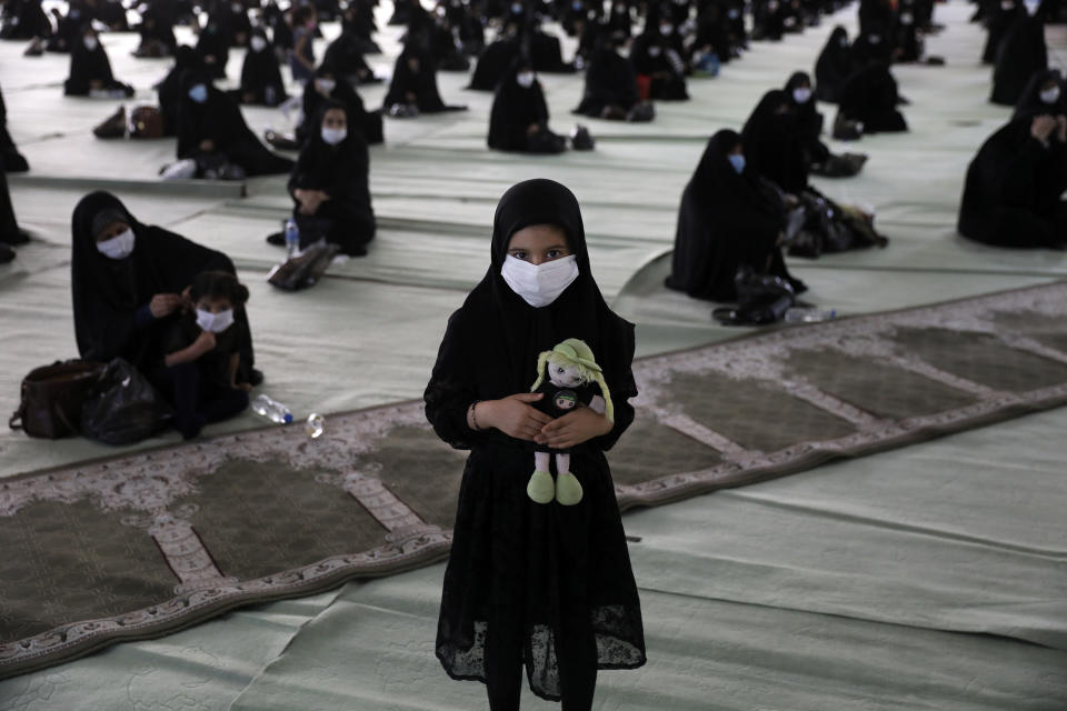 A girl wearing a protective face mask to help prevent spread of the coronavirus holds her doll as she attends a mourning ceremony to commemorate the 7th century death of Prophet Muhammad's grandson, Hussein, one of Shiite Islam's most beloved saints, who was killed in a battle in Karbala in present-day Iraq, at the Tehran University Musalla, Iran, Saturday, Aug. 29, 2020. The organizers arranged for the processions to take place with physical distancing, made face masks mandatory, checked mourners' body temperature and had them use hand sanitizers in an attempt to keep the gathering safe. Every year, millions of believers and followers of Shiite Islam flock to mosques for the ritual but this year the virus pandemic has scaled it down. (AP Photo/Vahid Salemi)