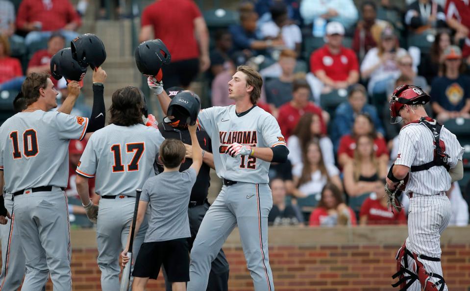 Oklahoma State's Colin Brueggemann (12) reacts after grand slam next to Oklahoma's Easton Carmichael (2) in the third inning during the Bedlam baseball game between the University of Oklahoma Sooners and the Oklahoma State University Cowboys at L. Dale Mitchell Park in Norman, Okla., Thursday, May, 18, 2023. 