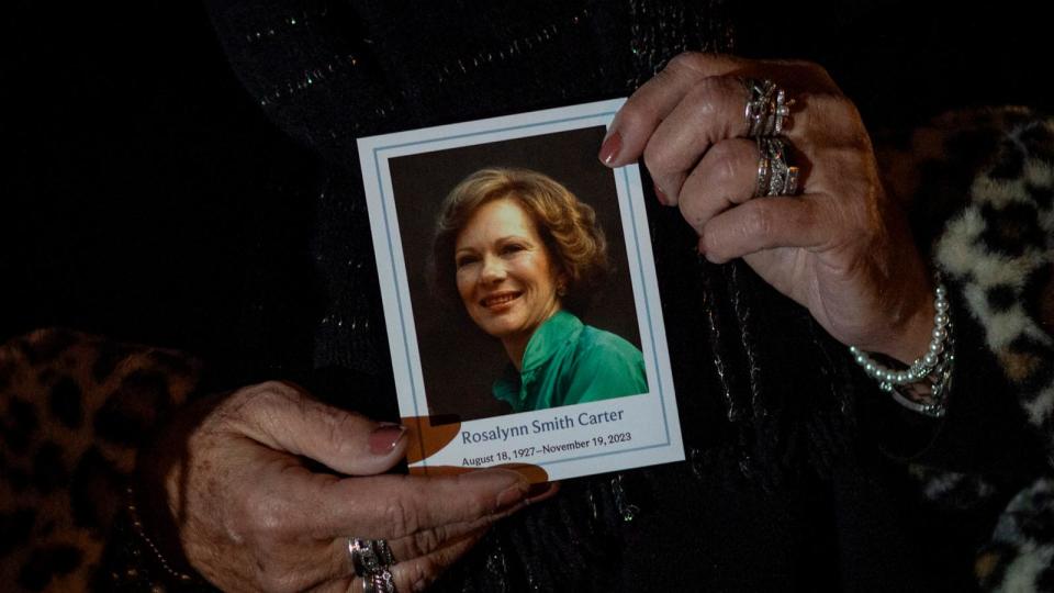 PHOTO: A woman holds a photo of former U.S. First Lady Rosalynn Carter as her body lays in repose at the Carter Presidential Library, Nov. 27, 2023, in Atlanta. (Christian Monterrosa/AFP via Getty Images)