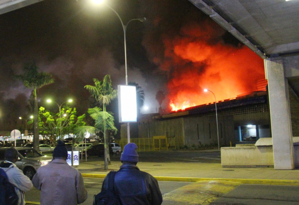 People watch a large blaze raging at the Jomo Kenyatta International Airport in Nairobi, Kenya, early Wednesday, Aug. 7, 2013. The Kenya Airports Authority said Wednesday that Kenya's main international airport has been closed until further notice so that emergency teams can battle the fire. (AP Photo/Kyodo News) JAPAN OUT, MANDATORY CREDIT