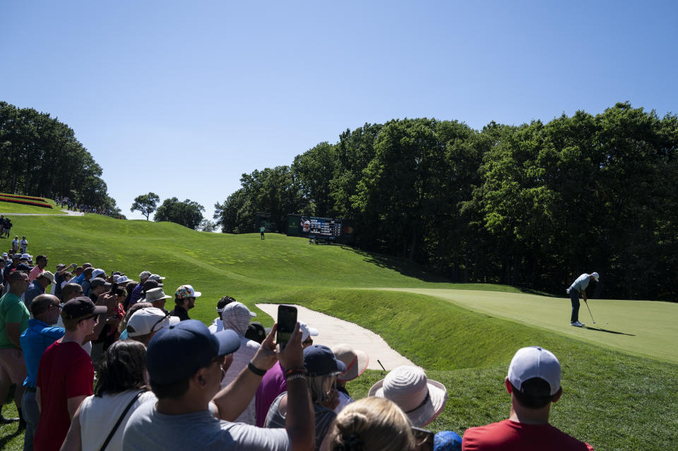 Dustin Johnson putts on the 11th green as spectators watch during the first round of the Travelers Championship golf tournament at TPC River Highlands, Thursday, June 24, 2021, in Cromwell, Conn. (AP Photo/John Minchillo)