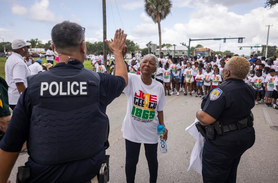 Marjorie Harrell (center) gets a high five from officer Damian Spotts (left), of the Fort Pierce Police Department, before the start of the Juneteenth Peace Walk in Fort Pierce on Friday, June 17, 2022. "I'm elated. We've been teaching them for 22 years about Juneteenth," said Harrell, chairperson for the Juneteenth Festival. "It's all about freedom and coming together. Everybody, white, black, everybody should celebrate it. We are the original forth of July."