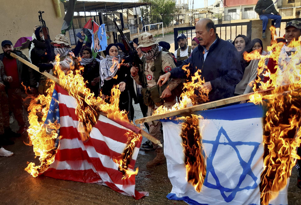 Palestinian gunmen and civilians burn the U.S. and the Israeli flags, during a protest against the White House plan for ending the Israeli-Palestinian conflict, at Ein el-Hilweh refugee camp, in the southern port city of Sidon, Lebanon, Wednesday, Jan. 29, 2020. At refugee camps across the country, Palestinians staged strikes, protests and sit-ins a day after U.S. President Donald trump revealed the long-awaited details of the plan, denouncing it as ridiculously lop-sided and saying it gives them no rights. (AP Photo/Mohammed Zaatari)