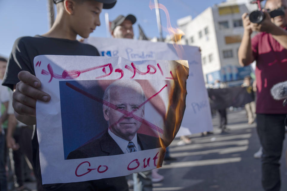 Palestinian activists burn defaced pictures of U.S. President Joe Biden while protesting his upcoming visit to the Palestinian territories, in the West Bank city of Ramallah, Thursday, July 14, 2022. Arabic reads "you are not welcome." (AP Photo/Nasser Nasser)