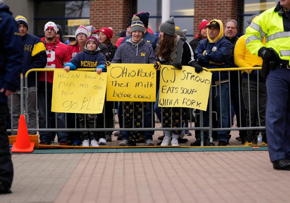 Fans hold signs as they wait for the teams to arrive prior to the NCAA football game between the Michigan Wolverines and the Ohio State Buckeyes at Michigan Stadium in Ann Arbor on Saturday, Nov. 27, 2021.