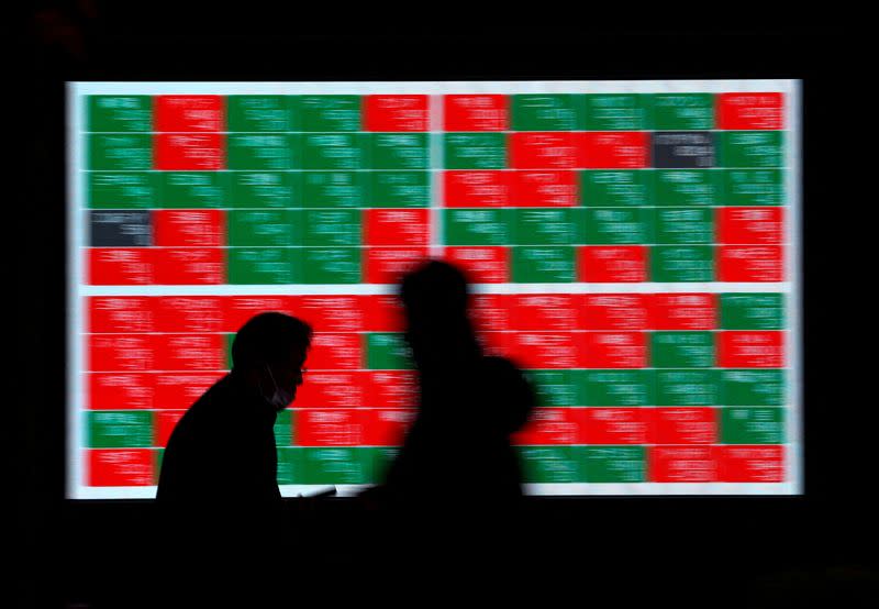 FILE PHOTO: Passersby walk past an electric stock quotation board outside a brokerage in Tokyo