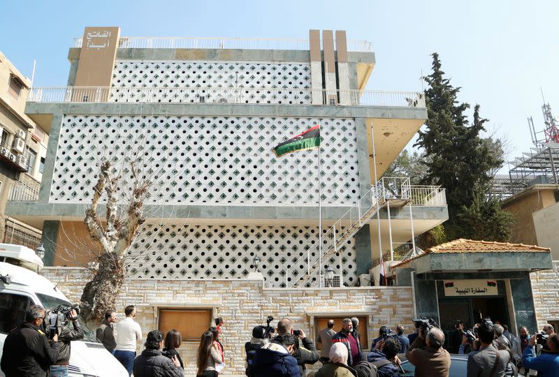 Journalists stand outside the embassy of Libya's eastern-based government led by military commander Khalifa Haftar, that opened in Damascus