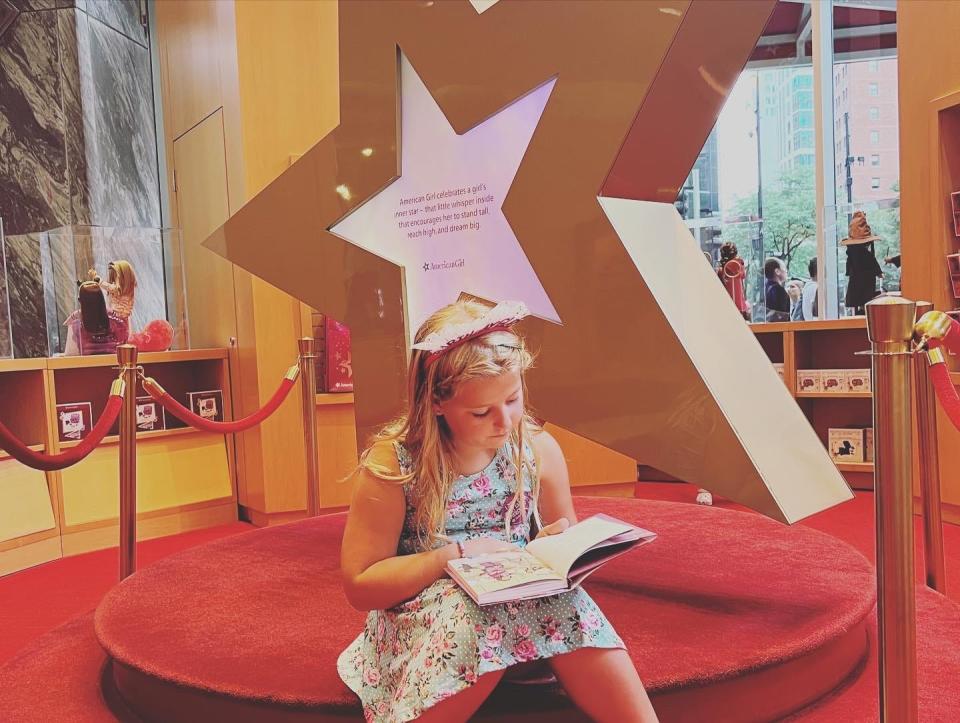 Girl reading a book at American Girl dolls store