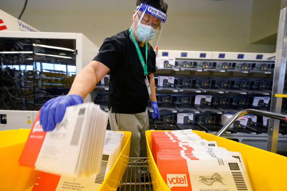 An election worker moves returned ballots from a sorting machine behind at the King County Elections office Tuesday, Oct. 20, 2020, in Renton, Wash. Election officials there said that 280,000 county ballots had already been returned, nearly 20% of the total sent to voters. Washington state is one of five states, along with Colorado, Hawaii, Oregon, and Utah, that conduct elections entirely by mail-in voting.