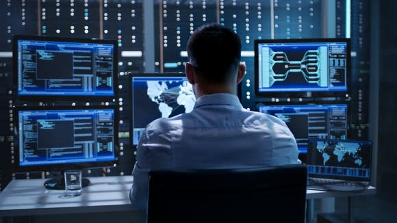 A person sitting in front of multiple computer screens