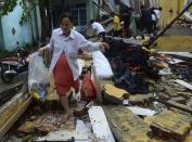 Nguyen Thi Ngoc Chau carries belongings through the remains of her home, which collapsed because of Typhoon Nari, in Vietnam's central Quang Nam province, October 15, 2013. Typhoon Nari knocked down trees and damaged hundreds of houses in central Vietnam early on Tuesday, forcing the evacuation of tens of thousands of people, state media said. More than 122,000 people had been moved to safe ground in several provinces, including Quang Nam and Danang city, by late Monday before the typhoon arrived, the official Tuoi Tre (Youth) newspaper reported. (REUTERS/Duc Hien)