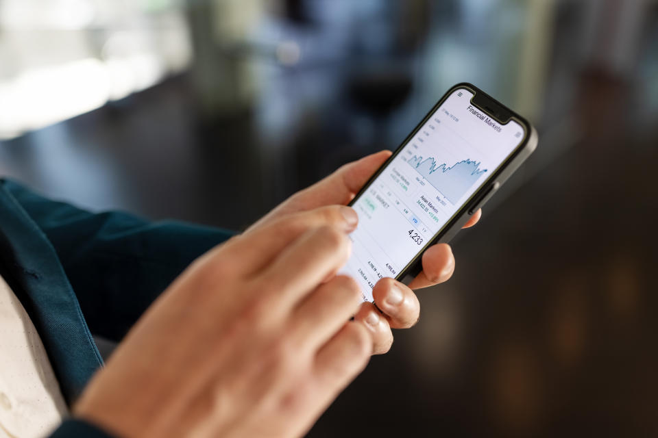 Close-up shot of businessman's hands using a mobile phone. Male professional is touching the display screen of the cell phone and sliding pages.