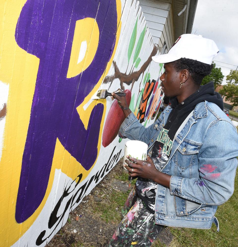 Artist Tony Wavy, formerly from Monroe, now living in Lexington, Ky., paints the final touches of his mural on the fence of the Selma Rankins Jr. Community Garden last week. Wavy's family was prominent in the neighborhood throughout his childhood in Monroe.