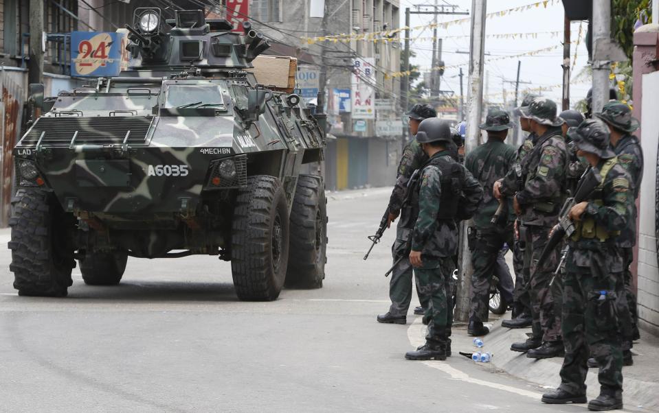 An armoured vehicle drives past government soldiers for another offensive against the Muslim rebels of Moro National Liberation Front (MNLF) positions in Zamboanga city