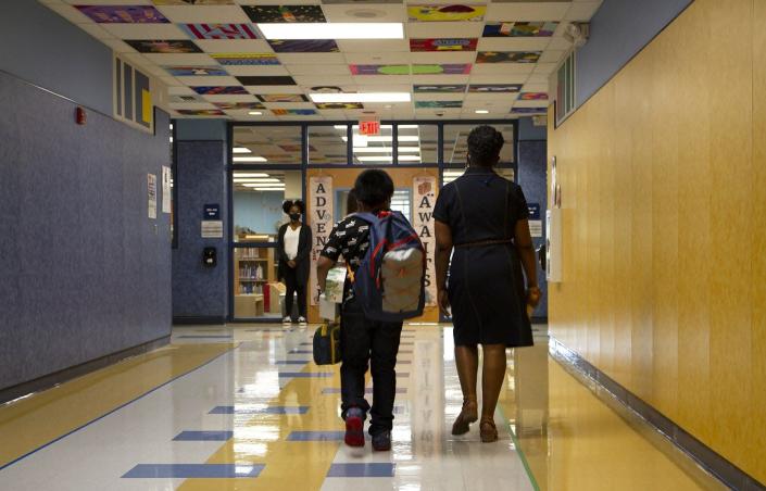 In this Aug. 15, 2021 file photo, special education teacher Michele Hunter walks a student to his classroom at Caldwell Elementary School in the Pflugerville school district.