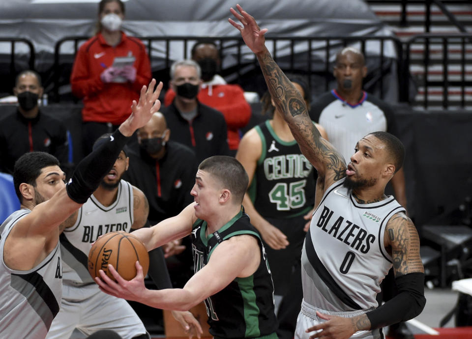 Boston Celtics guard Payton Pritchard, center, drives to the basket on Portland Trail Blazers center Enes Kanter, right, and guard Damian Lillard, right, during the first half of an NBA basketball game in Portland, Ore., Tuesday, April 13, 2021. (AP Photo/Steve Dykes)