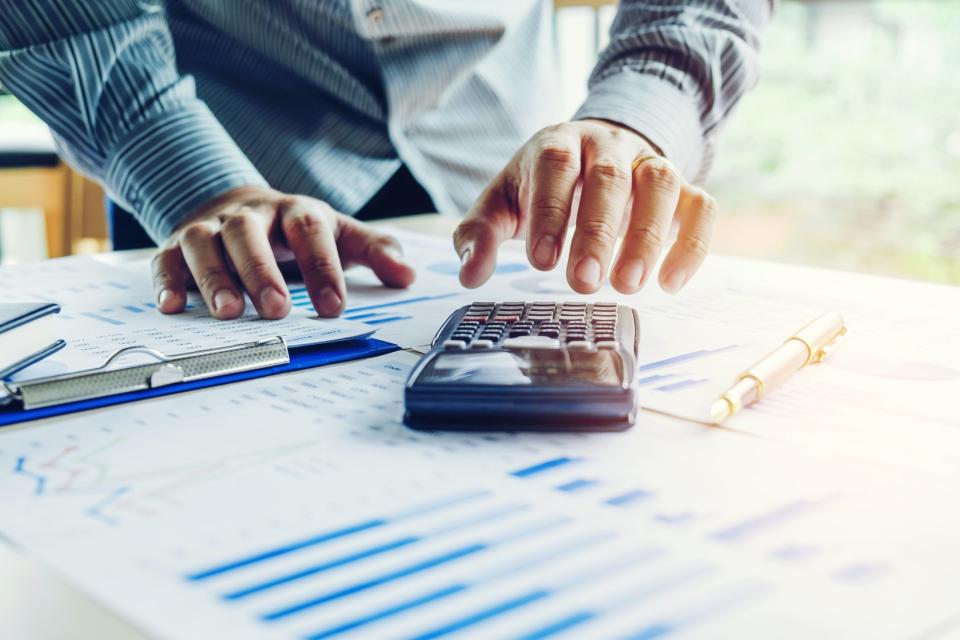 A person using a calculator with a pen and papers.