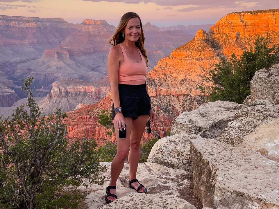 Emily stands on a rock overlooking the Grand Canyon at sunset.