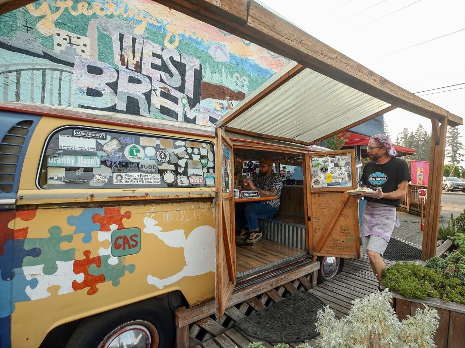 Lowell Yoxsimer carries a plate of moon biscuits and gravy to Brandon, Jenny and Iris Kindschy, who reserved the first weekend spot in the Volkswagon bus at Hi-Lo's 15th Street Cafe in Bremerton on Saturday.