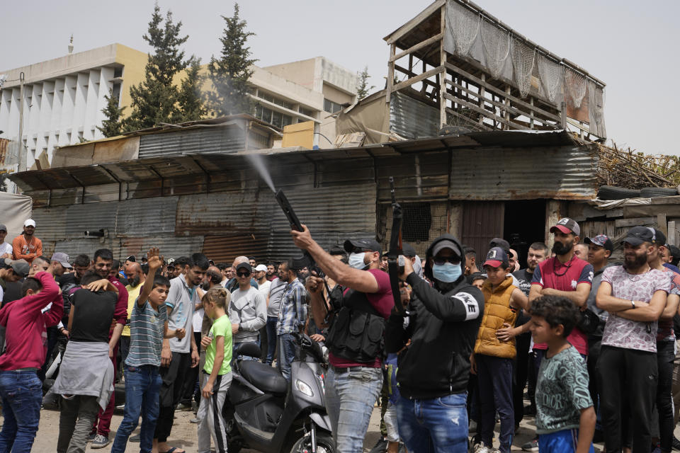 Gunmen fire in the air during the funeral procession for seven people killed when a boat packed with migrants sunk over the weekend as the Lebanese navy tried to force it back to shore, in Tripoli, north Lebanon, Monday, April 25, 2022. The small vessel was carrying nearly 60 people, many times its capacity, when the disaster struck on Saturday night. The tragedy was the latest in a growing trend involving mostly Lebanese and Syrians trying to travel to Europe from Lebanon in search of better lives. (AP Photo/Hassan Ammar)