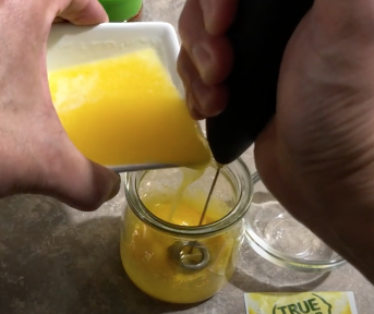 Blending a yellow sauce with a handheld milk frother