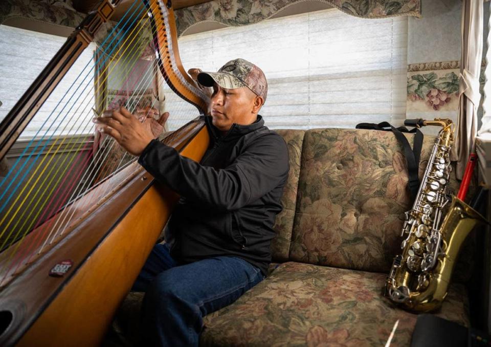 Luis Yauri Oyola practices on a harp that he brought from home and learned to play this year by watching YouTube videos while taking a break from tending to sheep in American Canyon on June 13, 2023. Some days he works from 6 a.m. until sundown. Other days the work only comes out to three hours per week. The rest of the time he watches soccer and practices playing his harp inside his trailer.