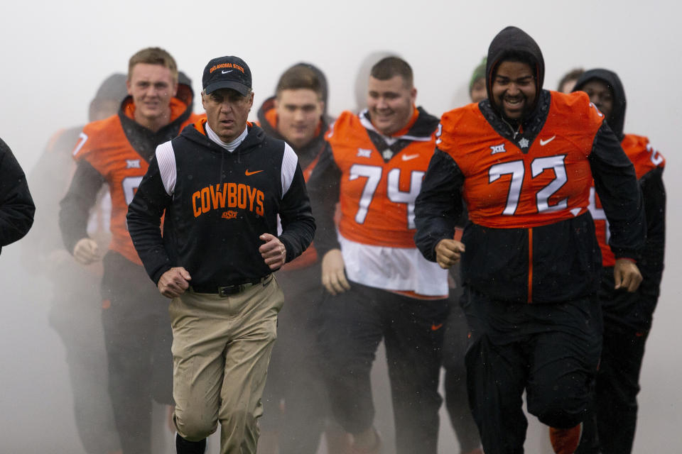 Oklahoma State head coach Mike Gundy leads injured players onto the field before the NCAA college football game against West Virginia in Stillwater, Okla., Saturday Nov. 26, 2022. (AP Photo/Mitch Alcala)