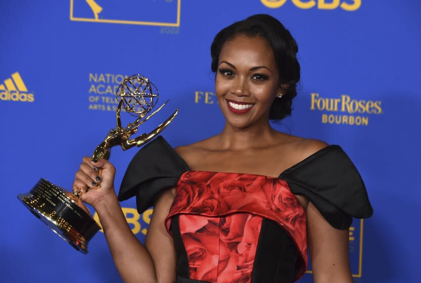 A woman wearing a red dress and holding a golden statue of a winged woman holding a globe