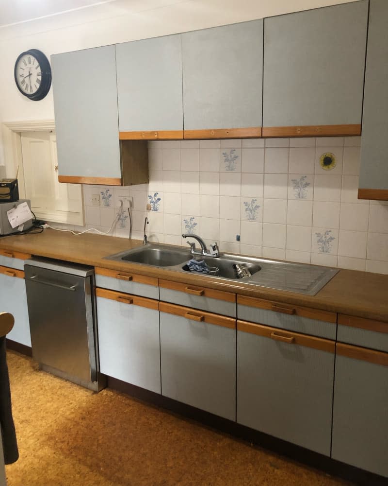 outdated smoke-stained kitchen with gray cabinets and white and blue tile backsplash before remodel