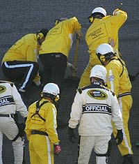 Officials work to repair a pothole in the middle of the Daytona 500 between Turns 1 and 2